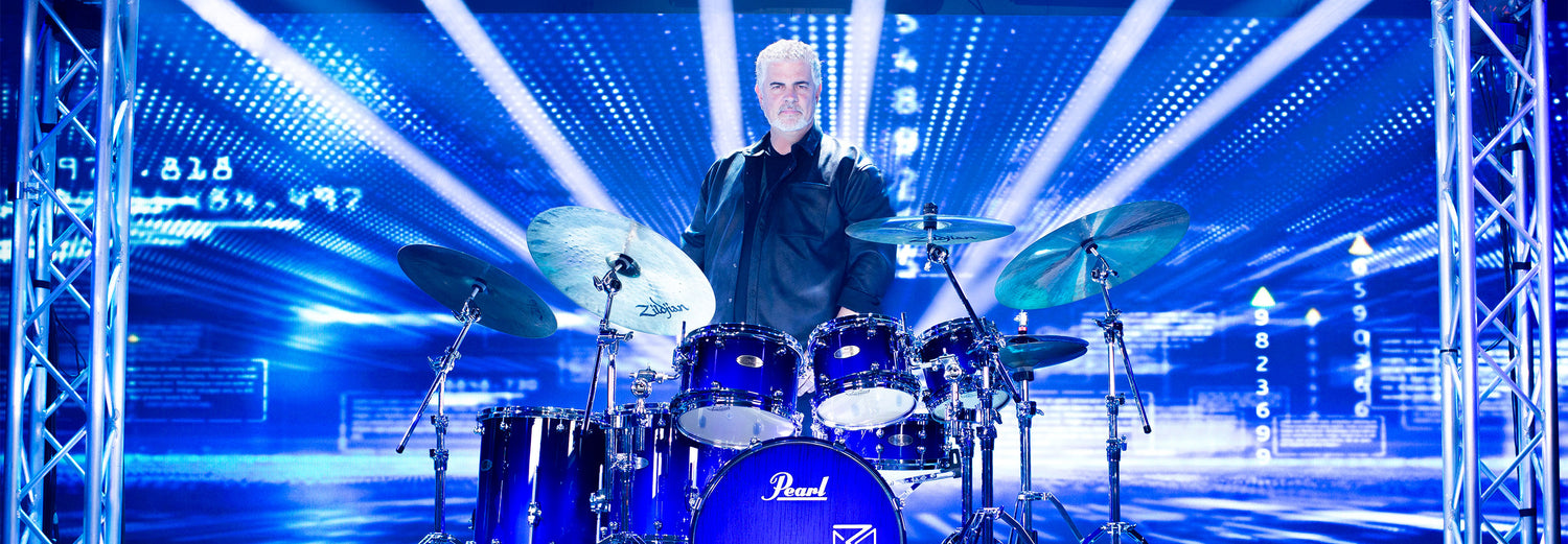 Russ Miller standing behind his drum kit on a stage with blue lighting