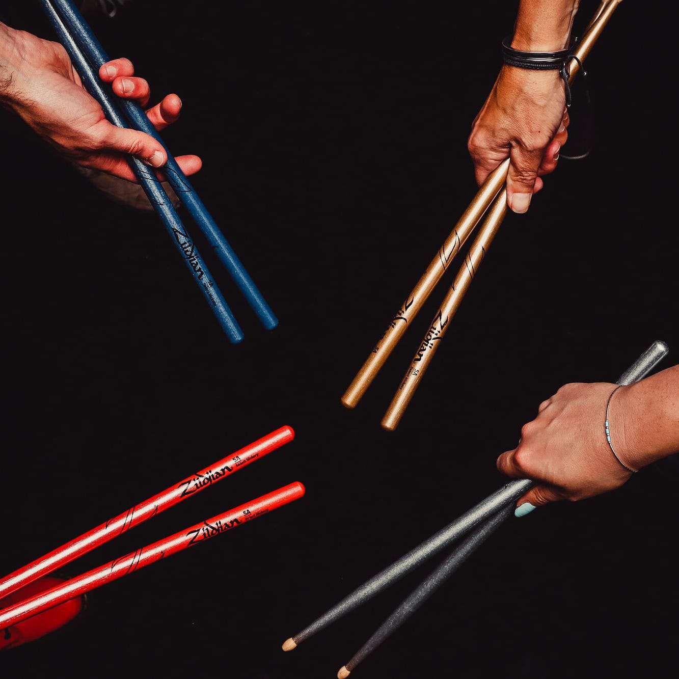All four color variation of the Chroma Zildjian 5a drumsticks being held by drummers
